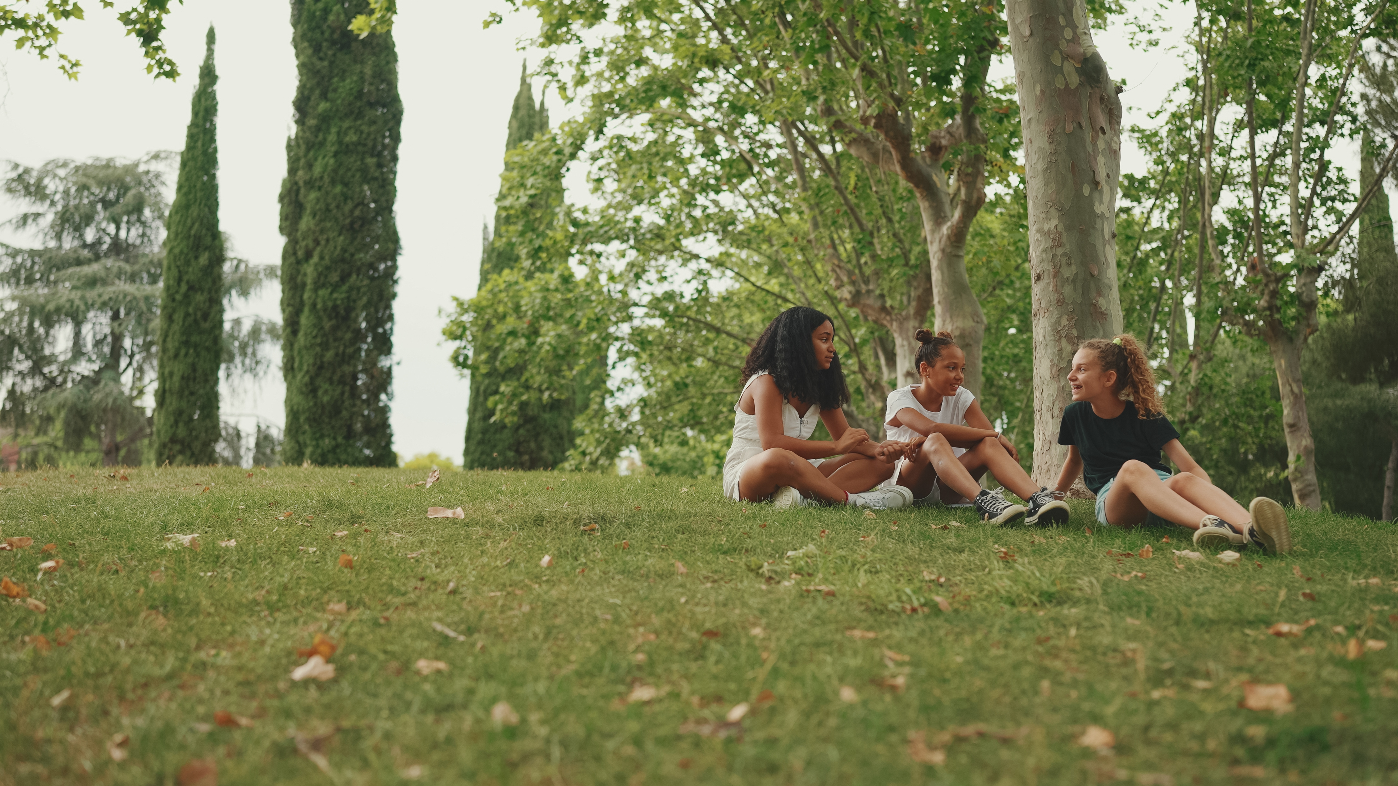 Three girls sitting together on the grass outdoors